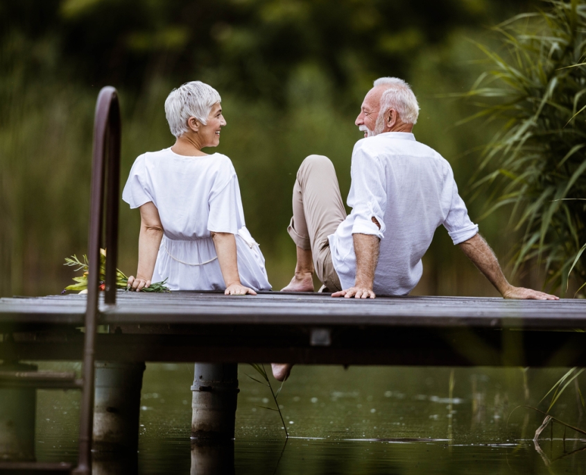 Rear view of happy senior couple talking on a pier.